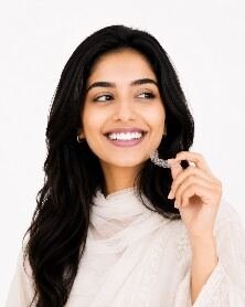 Patient smiling while holding a clear aligner