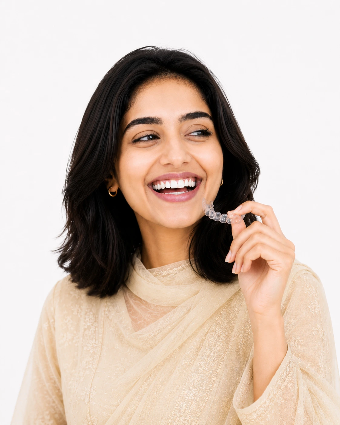 Woman smiling while holding a clear aligner tray near her face